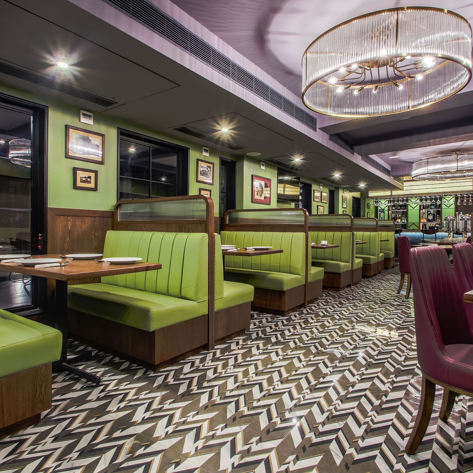 A retro-themed restaurant with green and purple booths, a tiled floor, and vintage-style lighting. 
